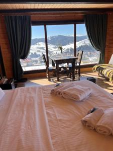 a bedroom with a bed with a table and a large window at Vysche Neba in Bukovel