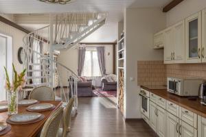 a kitchen with a table with chairs and a spiral staircase at Lillium in Merķeļi