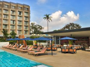 Mövenpick Kigali في كيغالي: مسبح مزود بكراسي ومظلات بجوار فندق