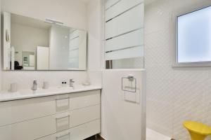 a white bathroom with a sink and a mirror at Quai Ouest - élégante maison avec piscine in Saint-Vincent-sur-Jard