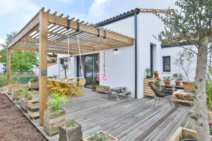 a wooden deck with a pergola and a table at La Bulle - Maison classée 4 étoiles in Brem-sur-Mer