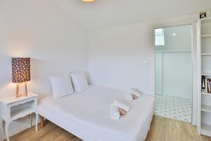 a bedroom with a white bed with a lamp and a window at La Bulle - Maison classée 4 étoiles in Brem-sur-Mer