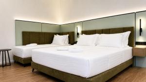 two beds in a hotel room with white pillows at Golden Nina Hotel in Vlorë +76 photos