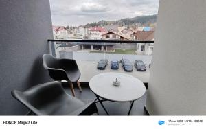 a balcony with chairs and a table and a view of cars at Zori de Bucovina in Gura Humorului