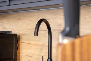 a kitchen sink with a faucet in front of a wooden wall at Modern 2-Bed Apartment, Greenock in Greenock