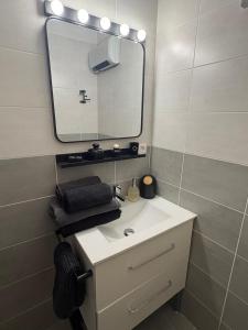 a bathroom with a white sink and a mirror at La Clef de la Place in Leucate