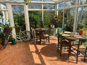 a patio with tables and chairs in a conservatory at Kermor B&B in Claddaghduff