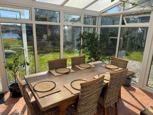 a wooden table in a conservatory with a table and chairs at Kermor B&B in Claddaghduff