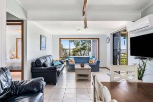 a living room with a couch and a tv at Spikes Place - Waterfront Serenity for Groups in Hindmarsh Island