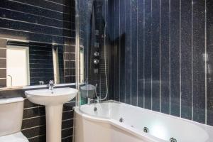 a bathroom with a sink and a tub and a toilet and a bath tub at Spacious 3-Bed Apartment, Alva, Clackmannanshire in Alva