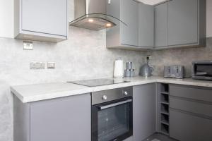 a kitchen with white cabinets and a sink at Spacious 3-Bed Apartment, Alva, Clackmannanshire in Alva +18 photos