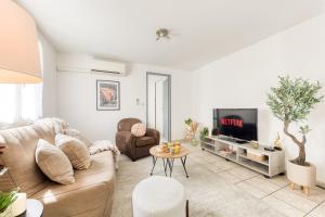 a living room with a couch and a tv at Cocon lumineux au centre de Tarbes, terrasse privée au soleil, confort tout inclus in Tarbes
