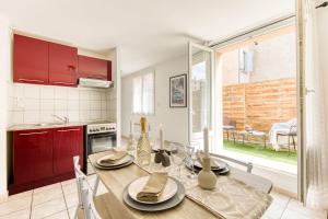 a kitchen with a wooden table and red cabinets at Cocon lumineux au centre de Tarbes, terrasse privée au soleil, confort tout inclus in Tarbes