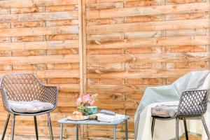 two chairs and a table in front of a wooden wall at Cocon lumineux au centre de Tarbes, terrasse privée au soleil, confort tout inclus in Tarbes +28 photos