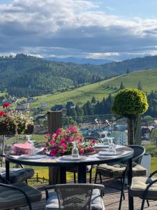 a table with flowers on a deck with a view at Vysche Neba in Bukovel