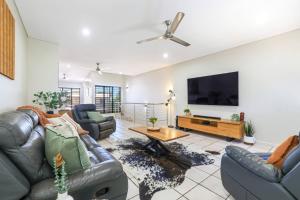 a living room with couches and a flat screen tv at Huge Stylish Townhouse in Stuart Park