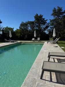 a swimming pool with chairs and umbrellas in a yard at Masseria Fagà in Otranto