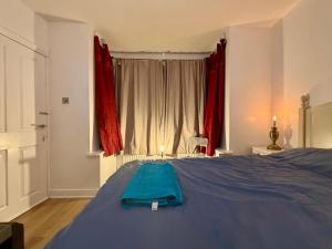 a bedroom with a blue bed with red curtains at Spacious Double Room with own Sink in Colindale