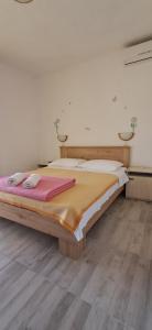a large bed in a room with a wooden floor at Pansion Maria in Zadar