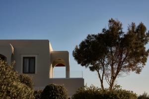 a house with a tree in front of it at Malena Hotel & Suites - Adults Only by Omilos Hotels in Amoudara Herakliou