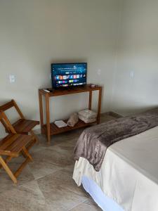 a room with a tv and a bed and a chair at Cerrado da Canastra Chalé Quartinho simples in São Roque de Minas +2 photos