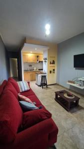 a living room with a red couch and a kitchen at Depto Baires Oeste Merlo in Merlo +3 photos