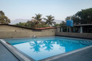 a swimming pool with a palm tree reflected in it at Amra Woods in Karjat +17 photos