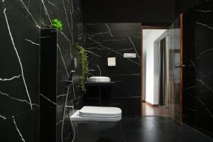 a bathroom with a toilet and a black wall at Amra Woods in Karjat