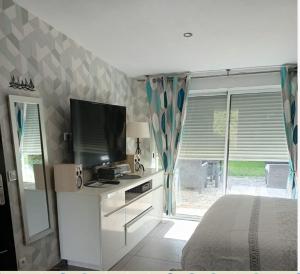 a bedroom with a bed and a television and a window at apartement avec parking prive in Concarneau