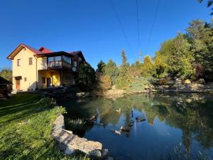 a house with a lake in front of it at Садиба "У Пані Галини" з форельним господарством in Kosiv