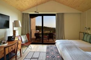 a bedroom with a bed and a desk and a balcony at Dream Guincho in Cascais +49 photos