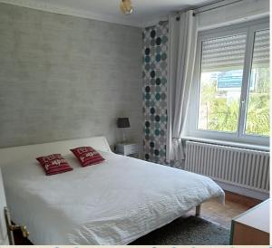 a bedroom with a bed with red pillows and a window at apartement avec parking prive in Concarneau