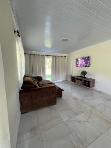 a large living room with a couch and a tv at Chácara com piscina, lazer e muita natureza in Morretes