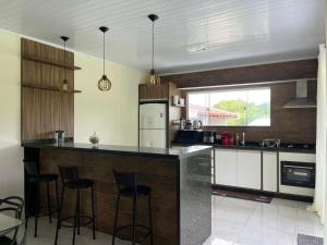 a kitchen with a counter with stools in it at Chácara com piscina, lazer e muita natureza in Morretes