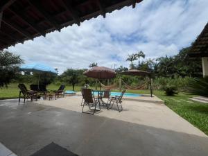 a patio with tables and chairs and umbrellas at Chácara com piscina, lazer e muita natureza in Morretes