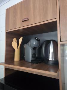 a kitchen cabinet with a coffee maker and a tea kettle at Aconchego in Concordia