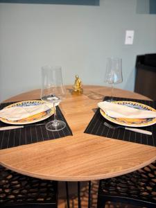 a wooden table with two wine glasses and plates on it at Residencial Zoe 101 in Foz do Iguaçu
