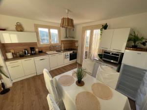 a kitchen with white cabinets and a table with chairs at Maison de Coco in LʼÉpine