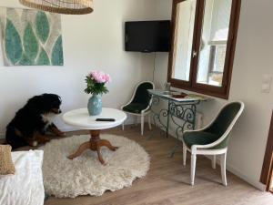 a dog sitting in a room with a table and chairs at Maison de Coco in LʼÉpine