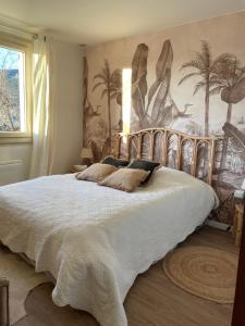 a bedroom with a large bed with a painting on the wall at Maison de Coco in LʼÉpine