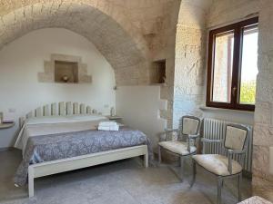 a bedroom with a bed and two chairs at Trullo Cuore di Pietra in Locorotondo
