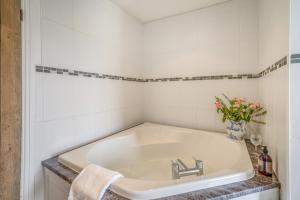 a white bathroom sink with a vase of flowers at Forge End Cottage Middleham in Middleham