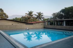 a swimming pool with a palm tree reflected in it at Amra Woods in Karjat