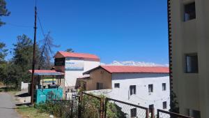 a white building with red roofs and a fence at The himaliyan munros in Rānīkhet
