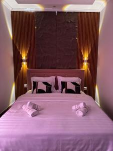 a bed with two pink slippers on top of it at Vila Silvi Bala in Pilur