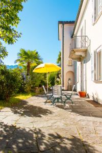 a patio with two chairs and a yellow umbrella at Villa dei Muralti - Homestay - Rooms rental in Muralto
