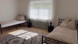 a bedroom with two beds and a window and a rug at Ferienwohnung Aiubi in Attnang-Puchheim