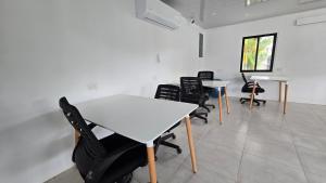 a room with tables and chairs and a white table at Mango Coliving Apartments for Digital Nomads in Uvita