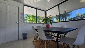 a dining room with a black table and white chairs at Mango Coliving Apartments for Digital Nomads in Uvita