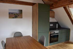 eine Küche mit einem Tisch und einem grünen Schrank in der Unterkunft Oderlandblick Apartment in Friedersdorf + 5 Fotos